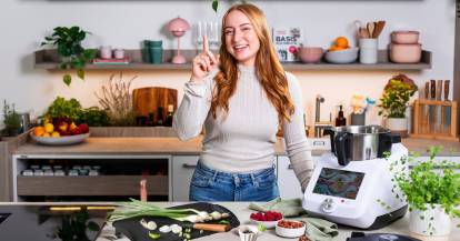 Junge Frau in einer Küche mit dem Monsieur Cuisine und einem Schneidebrett