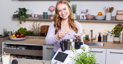 Junge Frau mit langen Haaren in einer Küche mit einem Monsieur Cuisine