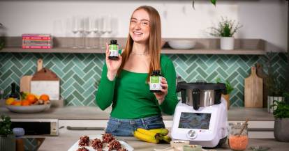 Eine junge Frau in einer Küche, in beiden Händen Gläschen mit Magnesium