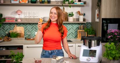 Junge Frau in einer Küche mit einem Eis in der Hand
