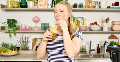 Junge Frau in einer Küche mit einem Eiskaffee