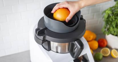 Jemand presse eine Orange auf dem Monsieur Cuisine mit dem WunderJuicer® aus