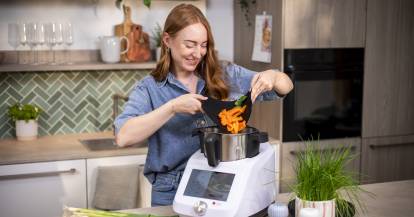 Frau gibt Gemüse in den Monsieur Cuisine