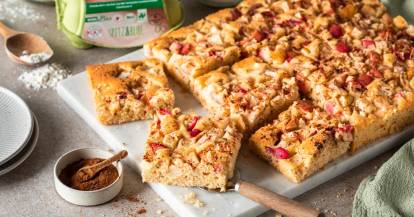 Apfelkuchen vom Blech, angeschnitten auf einer hellen Platte