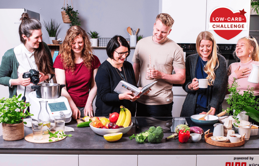 Sechs Personen hinter Arbeitsfläche mit Obst und Gemüse.