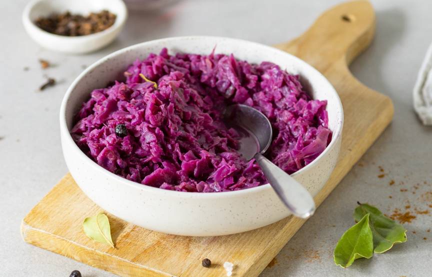 Rotkohl in einer Schale mit Löffel auf einem Holzbrett.