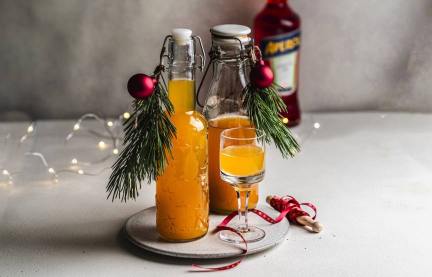 Zwei Flaschen mit orangefarbenem Likör, daneben ein Glas
