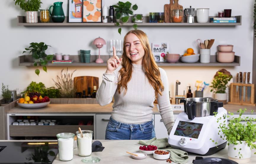 Junge Frau neben Monsieur Cuisine, zeigefinger erhoben