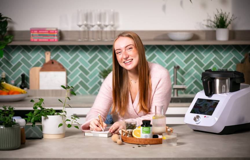 Junge Frau mit einem Monsieur Cuisine und Eisenpräparaten als Nahrungsergänzungsmittel