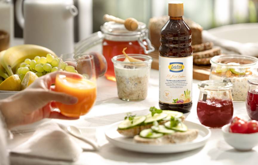 Frühstückstisch mit Obst, Gemüse, Saft und einer Flasche LaVita