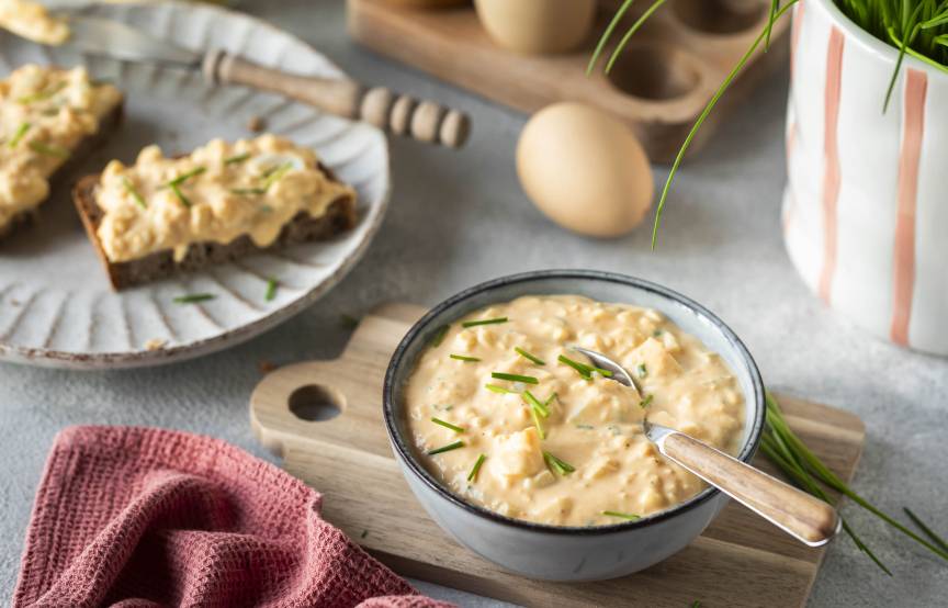 Eiersalat in einer Schale und auf Broten