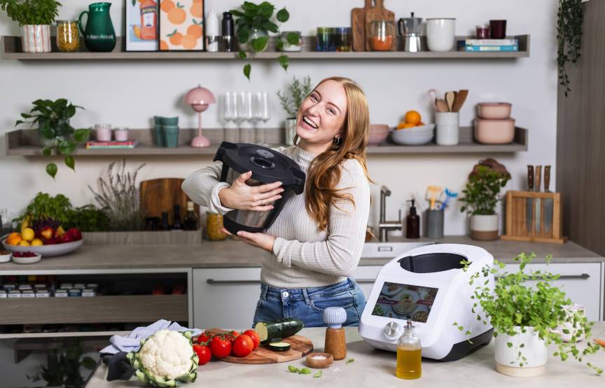 Junge Frau umarmt den Mixbehälter des Monsieur Cuisine