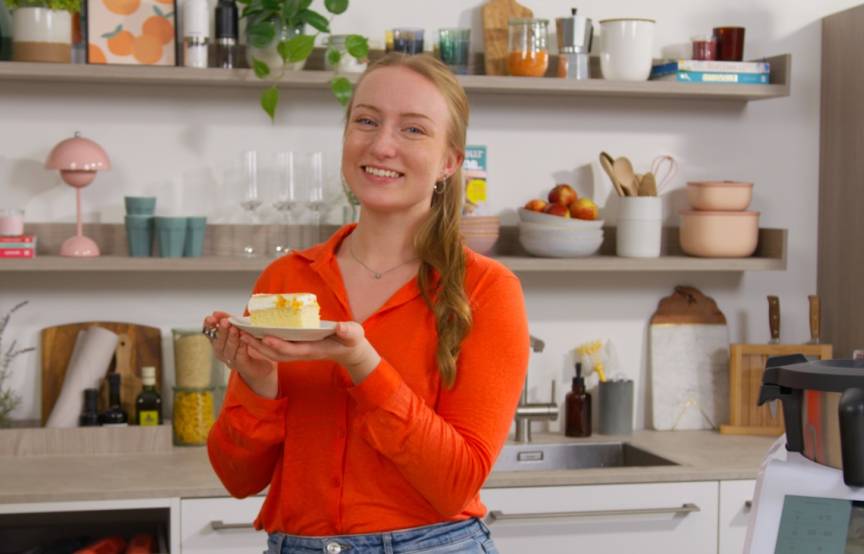 Junge Frau mit einem Stück Kuchen in einer Küche, neben dem Monsieur Cuisine