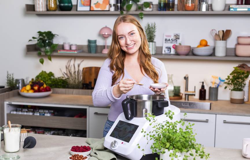 Junge Frau mit langen Haaren in einer Küche mit einem Monsieur Cuisine