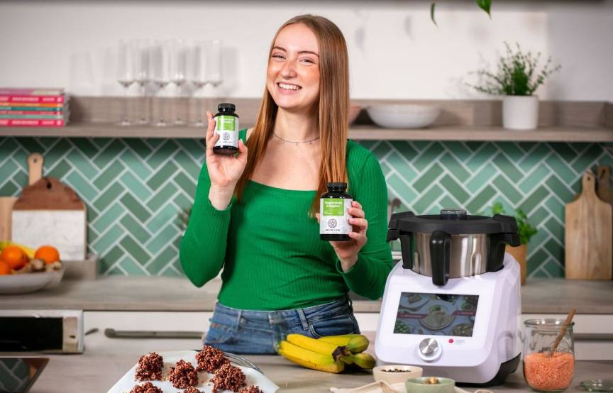 Eine junge Frau in einer Küche, in beiden Händen Gläschen mit Magnesium