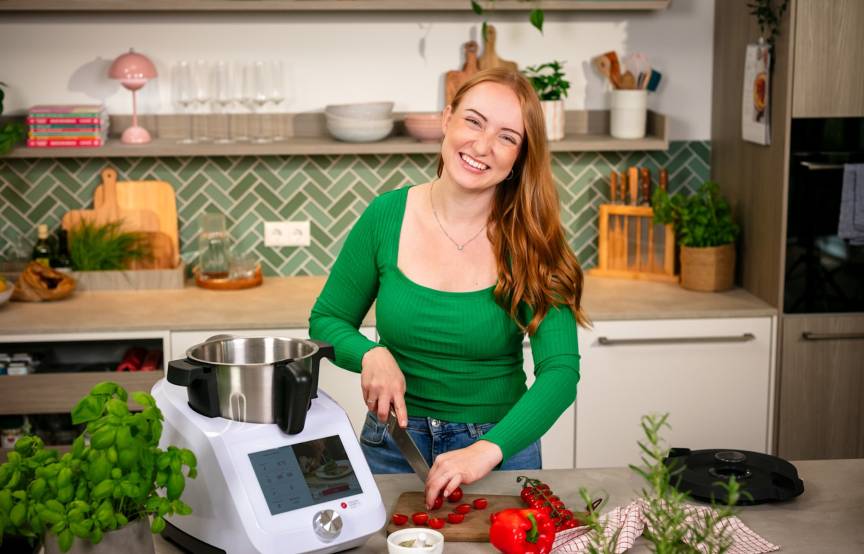 junge frau in einer küche, sie schneidet tomaten