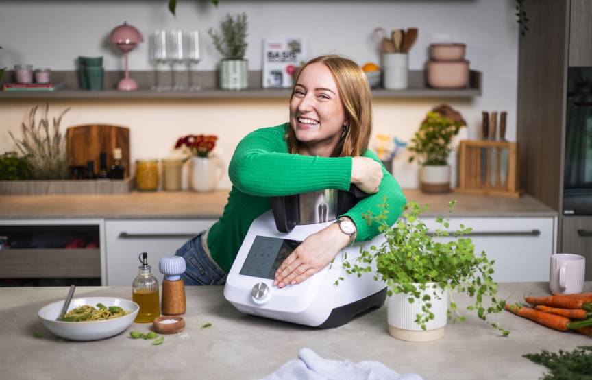 Junge Frau in einer Küche, umarmt den Monsieur Cuisine
