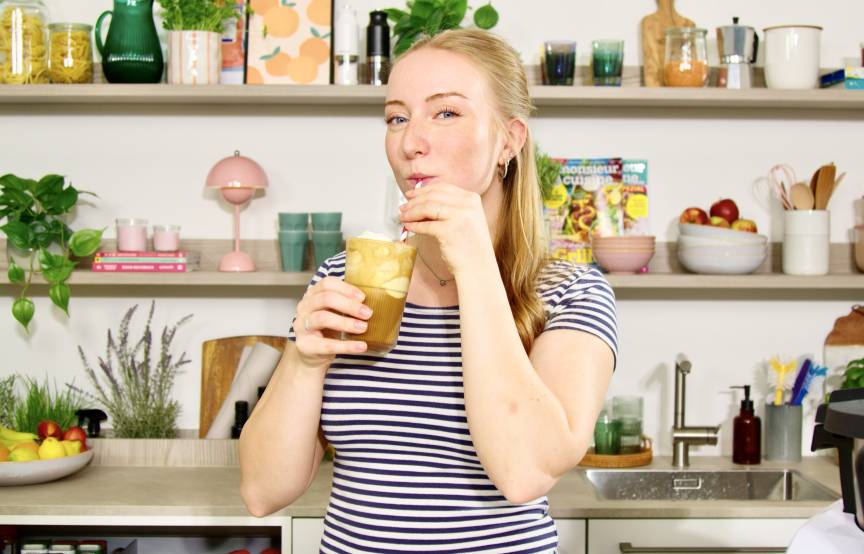 Junge Frau in einer Küche mit einem Eiskaffee