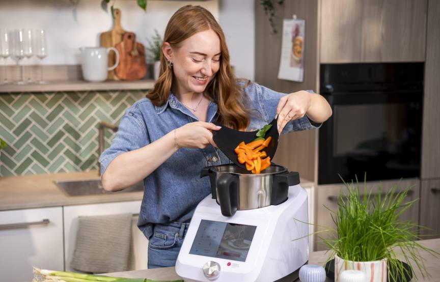 Frau gibt Gemüse in den Monsieur Cuisine