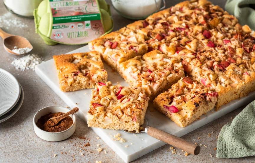 Apfelkuchen vom Blech, angeschnitten auf einer hellen Platte
