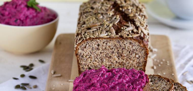 Gesundes Eiweißbrot angeschnitten und mit Rote-Bete-Creme bestrichen