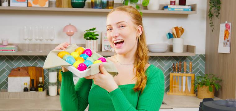 Isy hält einen Korb mit bunten Ostereiern Isy hält einen Korb mit bunten Ostereiern