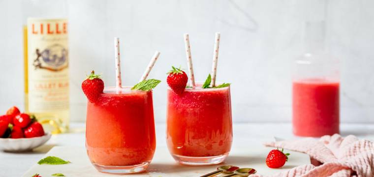 Zwei Gläser mit rotem Getränk und Strohhalmen vor hellem Hintergrund