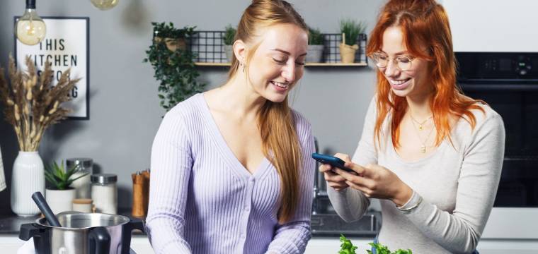 Zwei Frauen stehen neben dem Monsieur Cuisine und schauen auf ein Smartphone