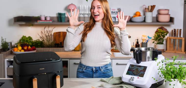 Junge Frau in einer Küche zwischen einem Airfryer und dem Monsieur Cuisine Junge Frau in einer Küche zwischen einem Airfryer und dem Monsieur Cuisine