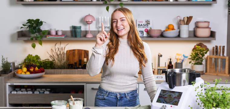 Junge Frau neben Monsieur Cuisine, zeigefinger erhoben