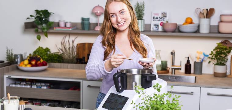 Junge Frau in einer Küche neben dem Monsieur Cuisine Junge Frau in einer Küche neben dem Monsieur Cuisine