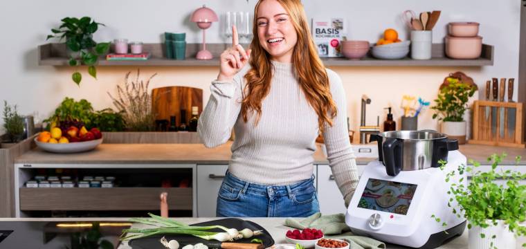 Junge Frau in einer Küche mit dem Monsieur Cuisine und einem Schneidebrett