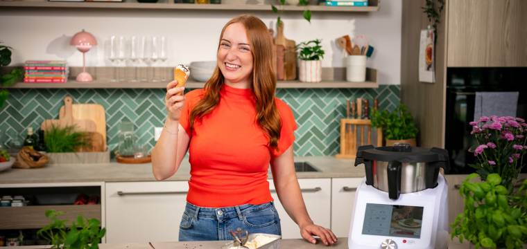 Junge Frau in einer Küche mit einem Eis in der Hand