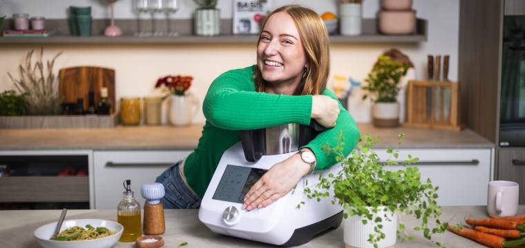 Junge Frau in einer Küche, umarmt den Monsieur Cuisine