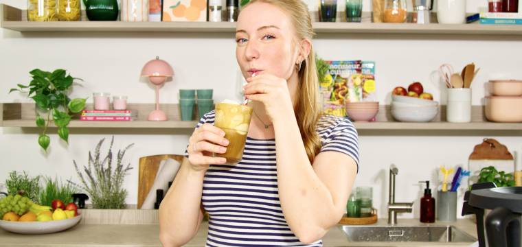 Junge Frau in einer Küche mit einem Eiskaffee Junge Frau in einer Küche mit einem Eiskaffee