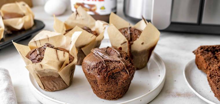 Schokomuffins mit Nutella auf einem Teller vor einem Airfryer Schokomuffins mit Nutella auf einem Teller vor einem Airfryer