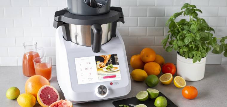 Monsieur Cuisine mit einem Aufsatz zum Saftpressen und umgeben von Zitrusfrüchten Monsieur Cuisine mit einem Aufsatz zum Saftpressen und umgeben von Zitrusfrüchten