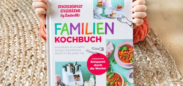 Ein Kind hält ein Familien-Kochbuch in die Kamera Ein Kind hält ein Familien-Kochbuch in die Kamera