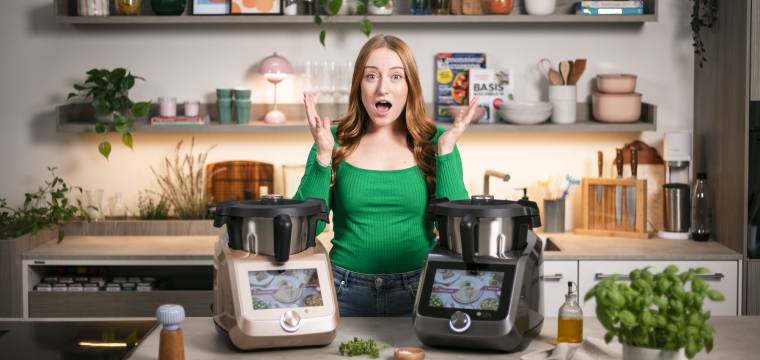Frau in einer Küche mit überraschtem Gesicht. Vor ihr zwei Monsieur Cuisine Frau in einer Küche mit überraschtem Gesicht. Vor ihr zwei Monsieur Cuisine