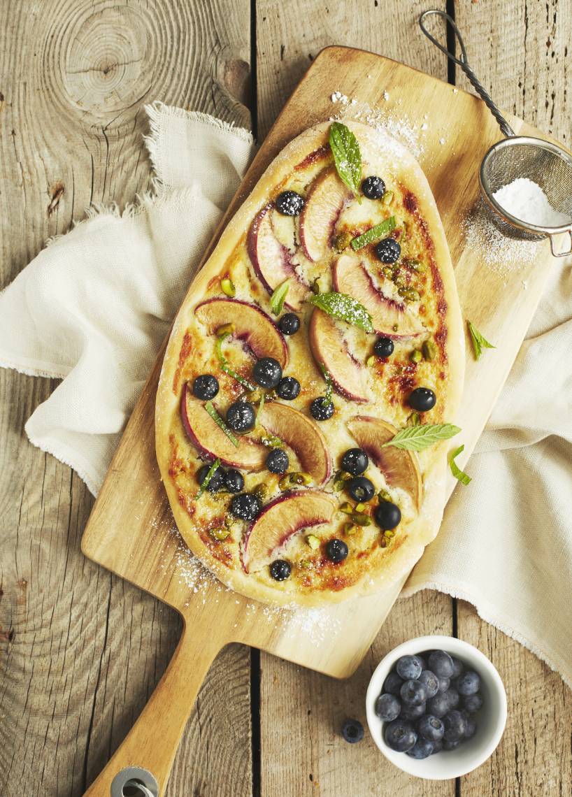 Süße Pizza mit Pfirsichen und Blaubeeren