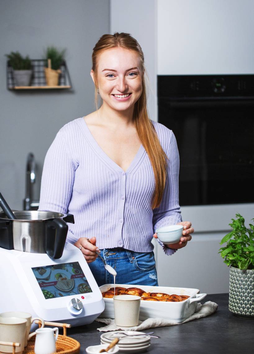 Junge Frau in Küche mit Monsieur Cuisine backt Zimtschnecken