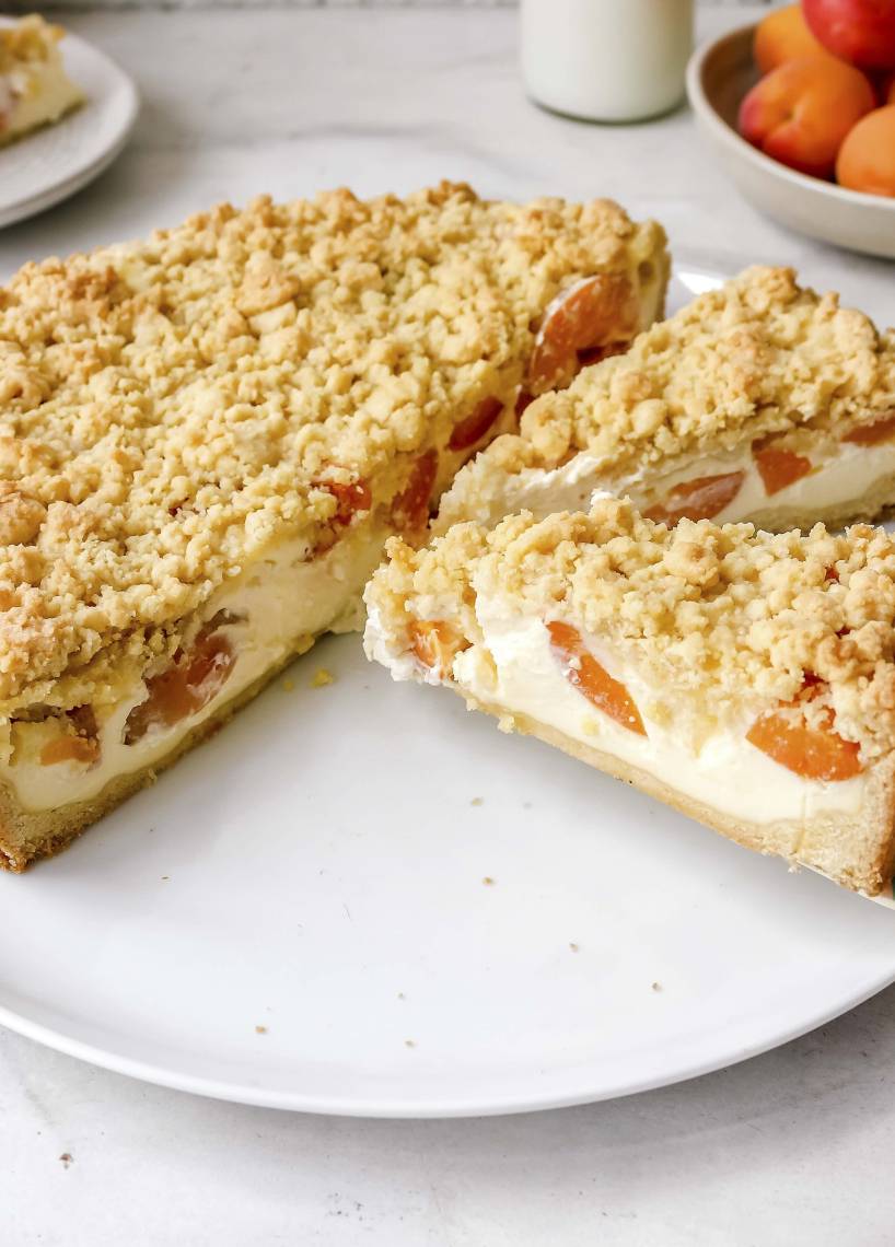 Kuchen angeschnitten mit Schmand, Aprikosen und Streuseln