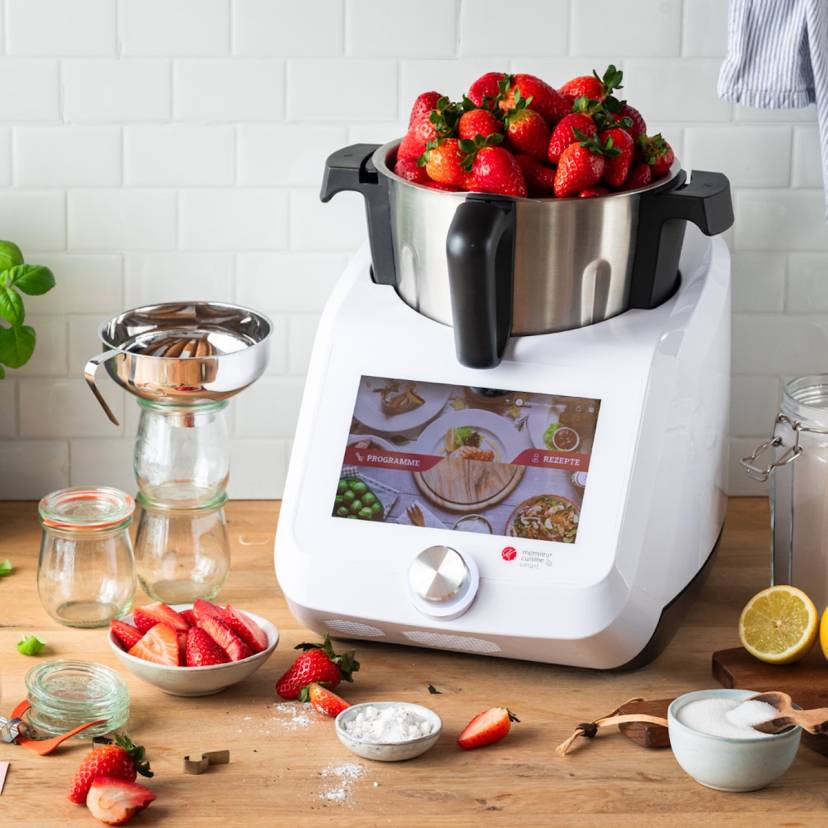 Der Monsieur Cuisine auf einer Arbeitsplatte aus Holz, im Mixbehälter sind Erdbeeren, die über den Rand schauen