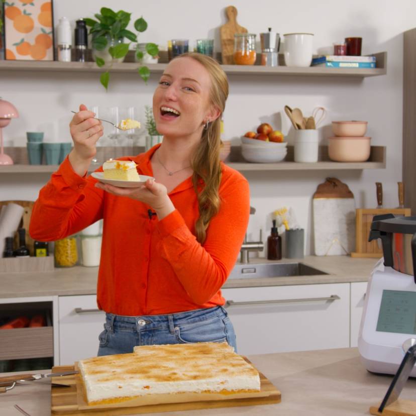 Isy isst ein Stück Kuchen und steht neben dem Monsieur Cuisine