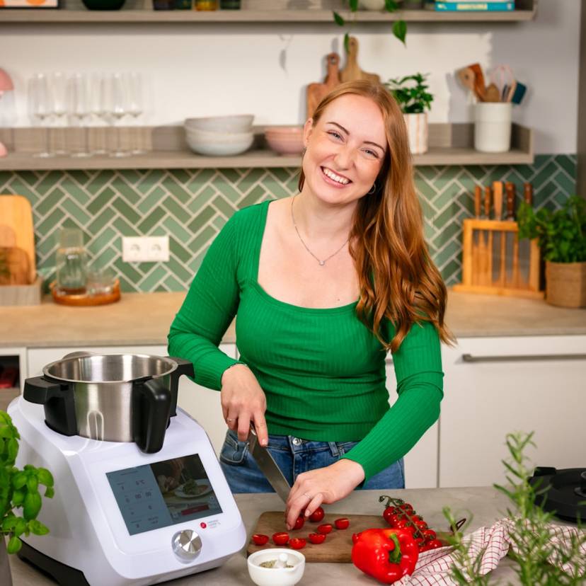 Frau mit langen, rötlichen Haaren schneidet Tomaten, daneben ein Monsieur Cuisine