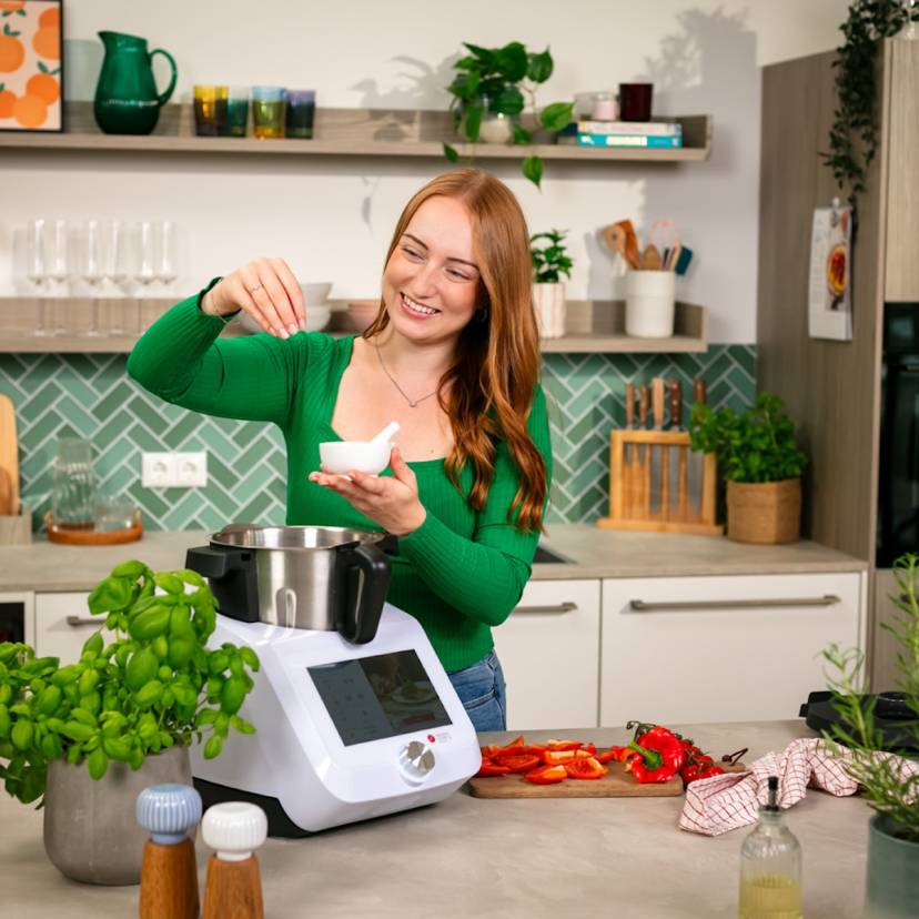 Eine junge Frau gibt etwas in den Monsieur Cuisine