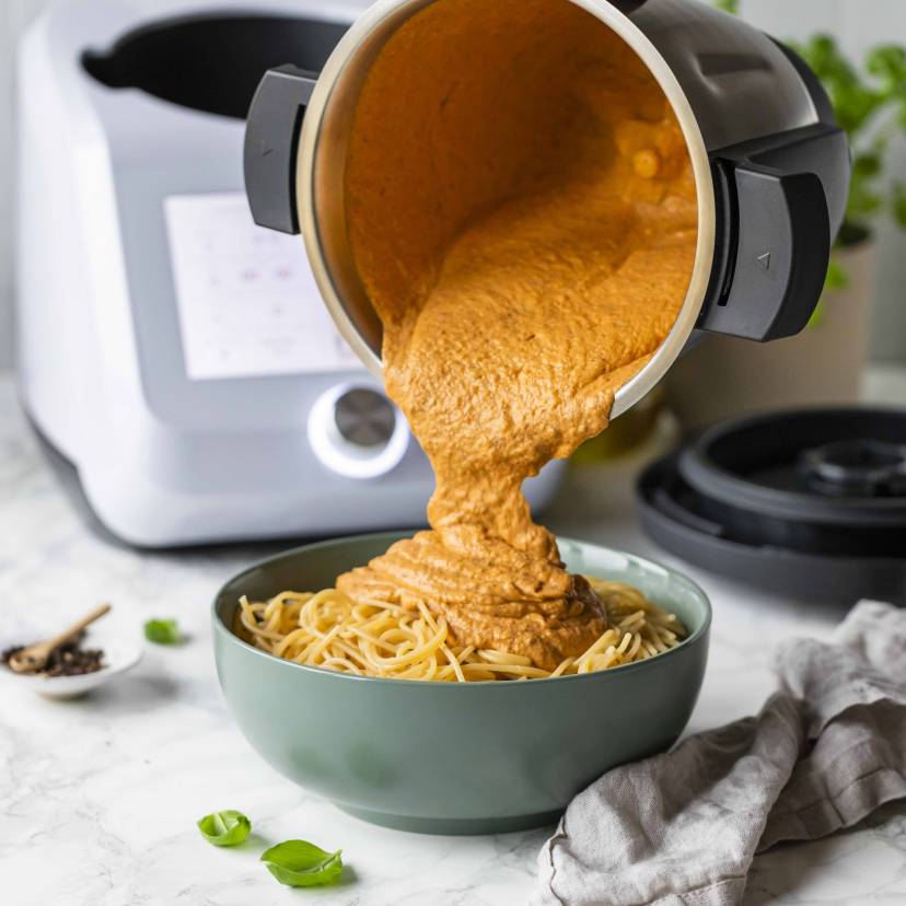 Dicke Tomatensoße wird auf eine Schüssel mit Spaghetti gekippt