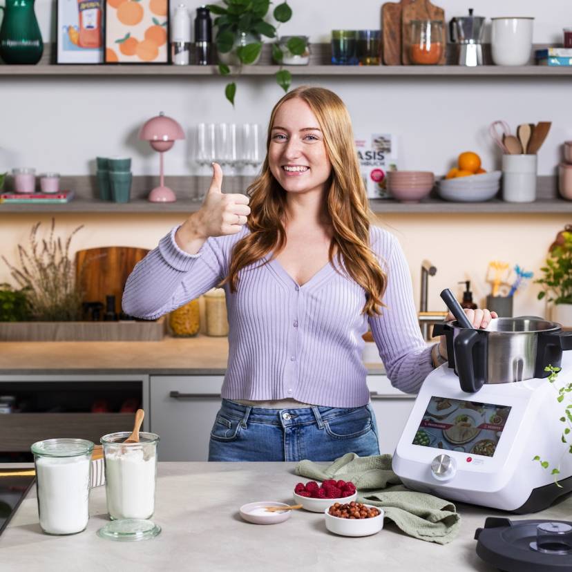 Junge Frau in einer Küche neben dem Monsieur Cuisine, hebt den Daumen