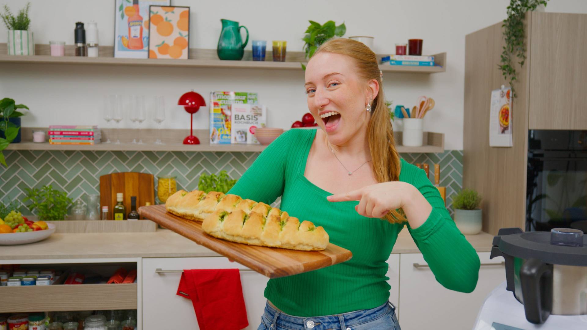 Isy zeigt auf zwei Kräuterbaguettes auf einem Holzebrett