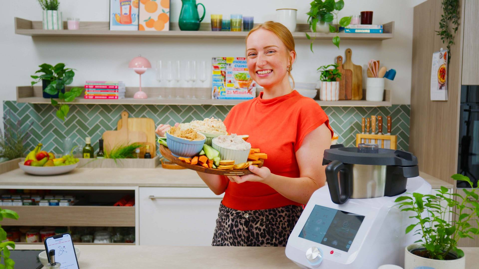 Isy hält ein Teller mit 3 Schüsseln mit verschiedenen Dips und Gemüse